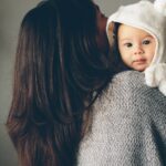 Mother holding young baby. baby is facing the camera, mothers head is turned away