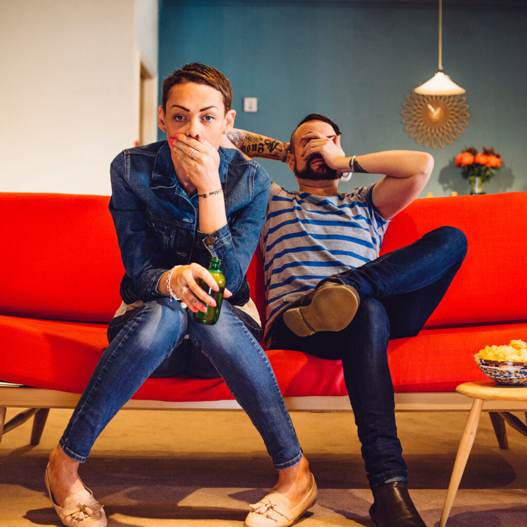 foster parents on red sofa looking shocked cant believe it